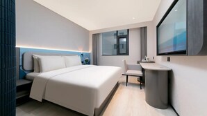 Una habitación de hotel moderna con una cama grande, un escritorio y un ventanal amplio.