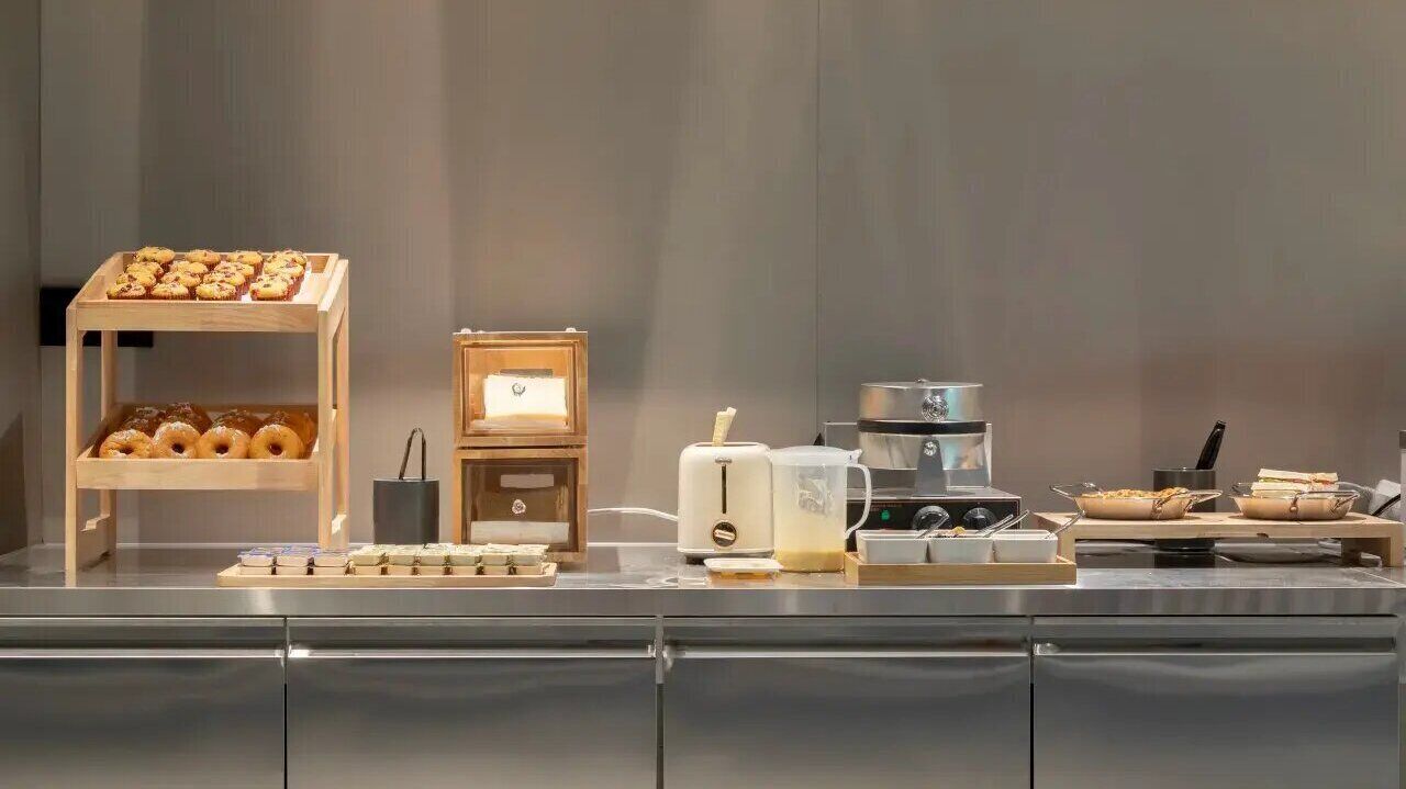 A buffet setup with a variety of food items, a coffee machine, and a small refrigerator.