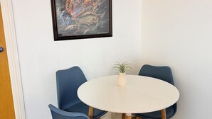 Ett rum med ett runt, vitt bord, fyra blå stolar och ett inramat konstverk på väggen.