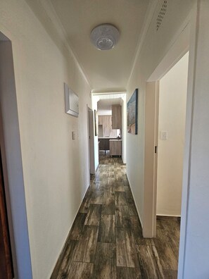 Un pasillo con piso de madera que conduce a una zona de cocina.