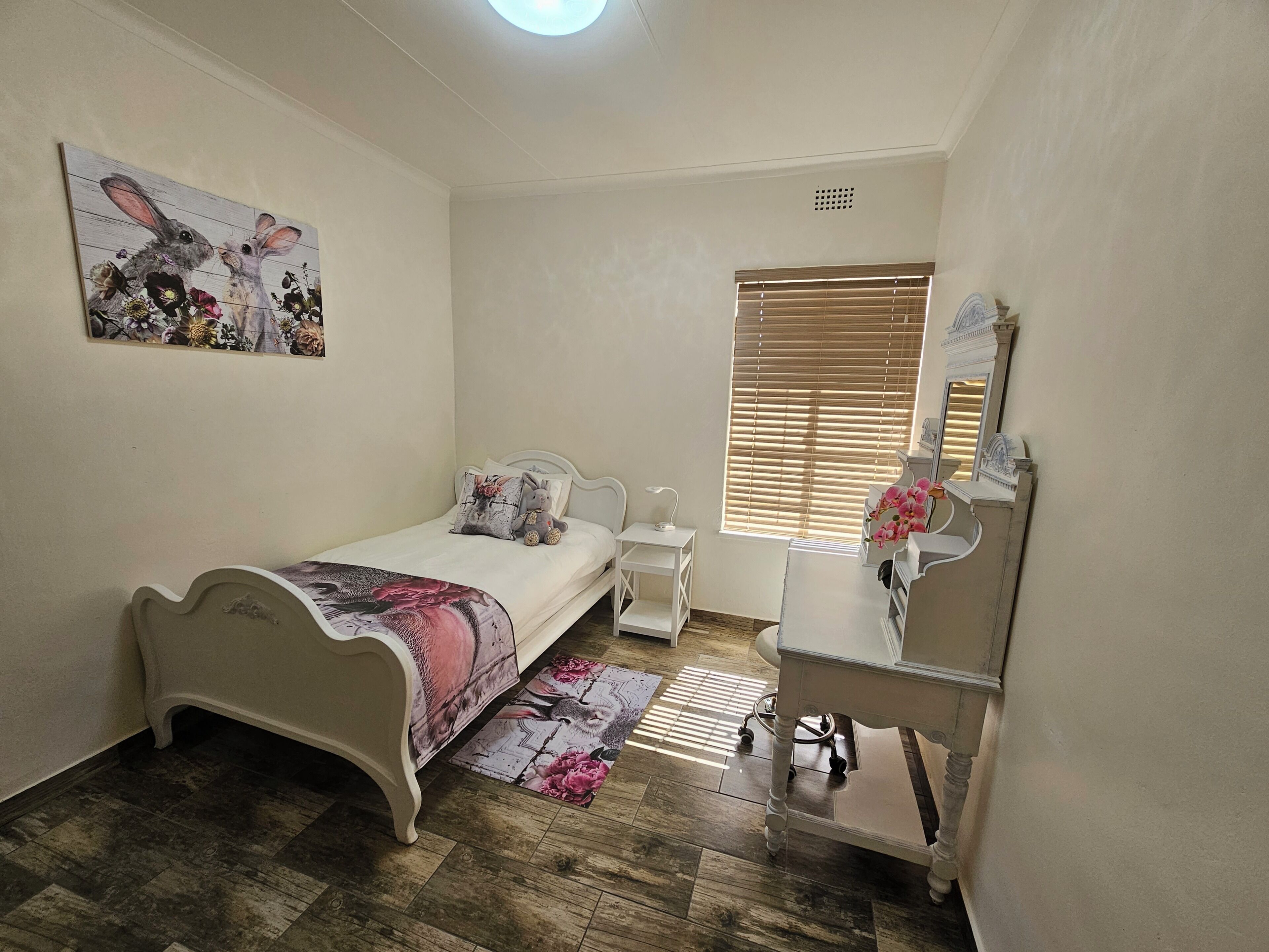 Un dormitorio con cama, mesita de noche, lámpara, cómoda y una ventana con persianas.