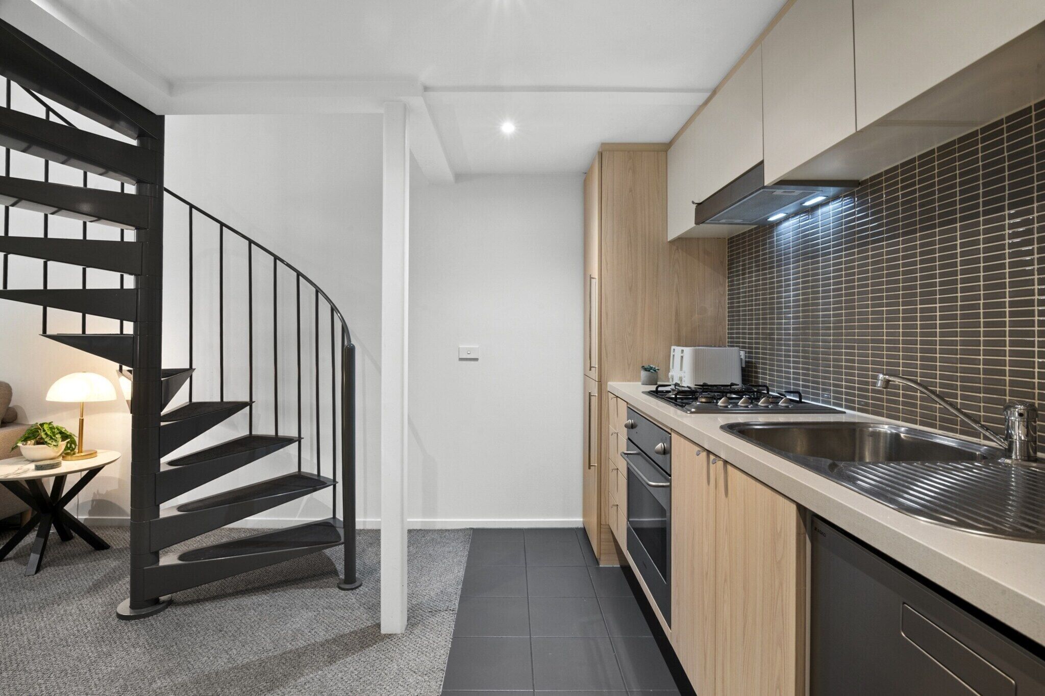 A modern kitchen with a built-in stove, a sink, and wooden cabinets.