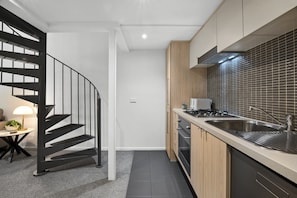 A modern kitchen with a built-in stove, a sink, and wooden cabinets. - Heritage Loft | Degraves Lane Melbourne CBD (Melbourne)