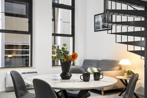 A modern living room with a round table, two chairs, a sofa, a coffee table, a floor lamp, and a staircase. - Heritage Loft | Degraves Lane Melbourne CBD (Melbourne)