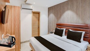 Ein modernes Hotelzimmer mit einem Holzkopfteil, einem flachbildfernseher an der Wand, einem Nachttisch mit Wasserkocher und Tassen sowie einer Holztür.