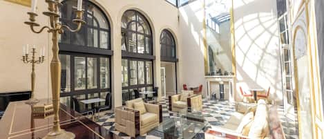 A spacious lobby with a checkered floor, seating areas, and a glass ceiling.