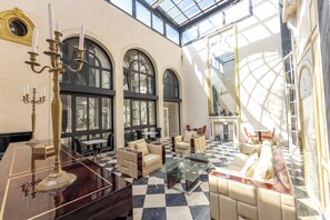 Eine großzügige Lobby mit Schachbrettmuster-Boden, Sitzbereichen und einer Glaskuppel.