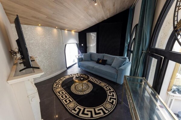 Una sala de estar moderna con un sofá azul, una mesa de centro redonda y un tapete decorativo.