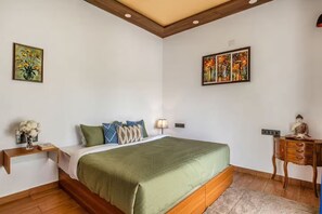 Ein Schlafzimmer mit einem Bett, einem Nachttisch, einer Lampe und Kunstwerken an den Wänden.
