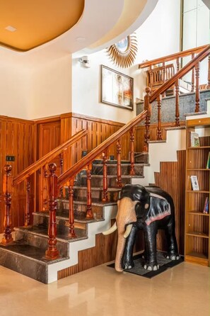 A grand staircase with wooden balusters and a marble landing, leading to a second floor. - Private Beach Villa (Alappuzha)
