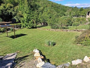 A grassy outdoor area with a stone wall, a wooden bridge, and a small shed. - Le MARMARE Vacation Rental (Caussou)