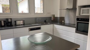 A modern kitchen with stainless steel appliances, a dishwasher, and a large glass bowl on the counter. - Le MARMARE Vacation Rental (Caussou)