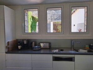 A kitchen with a window, a coffee maker, a toaster, and a sink. - Le MARMARE Vacation Rental (Caussou)