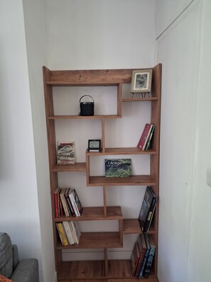 A wooden bookshelf with various books and a small framed picture. - Le MARMARE Vacation Rental (Caussou)