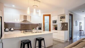 Eine moderne Küche mit einer zentralen Kochinsel, Barhocker, einer Mikrowelle und einer Kaffeemaschine.