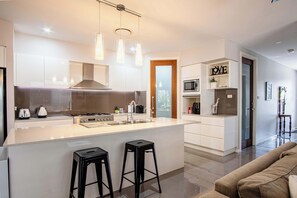 Una cocina moderna con una isla central, taburetes de bar, un microondas y una cafetera.