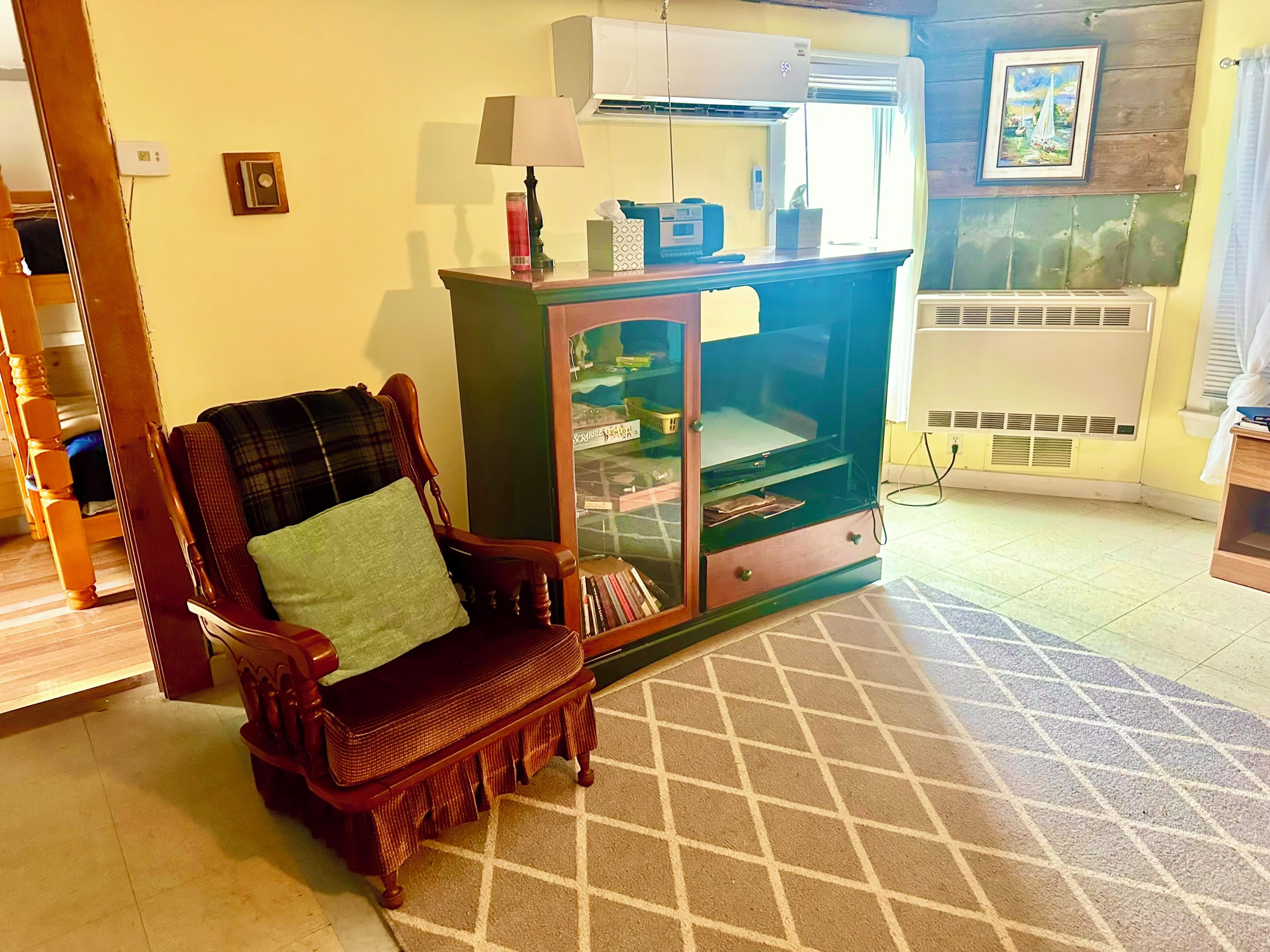 Un salon avec une chaise en bois, un meuble avec des portes en verre et un sol carrelé.