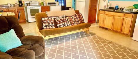 A living room with a sofa, a coffee table, and a kitchen area with appliances.