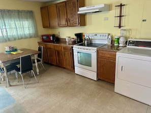 A kitchen with wooden cabinets, a microwave, a stove, and a refrigerator. - Peaceful 3-bedroom Cabin in Verona Beach (Verona Beach)