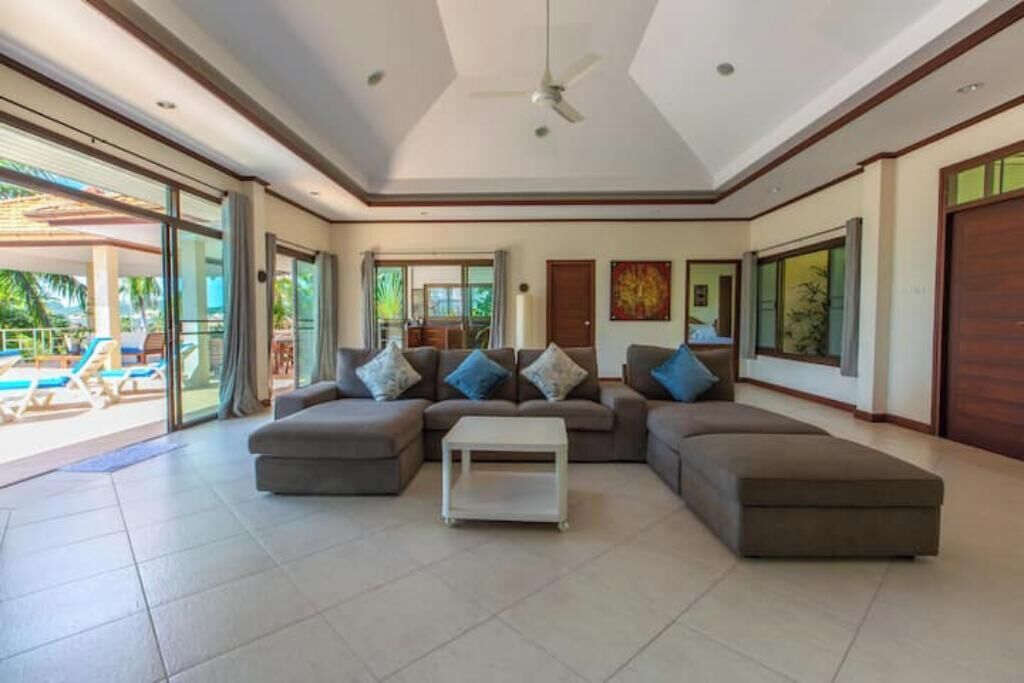 A spacious living area with a large sectional sofa, a coffee table, and a ceiling fan.