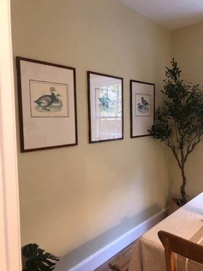 A wall with three framed pictures of ducks, a potted plant, and a table with a white tablecloth. - Pet-Friendly Woodland Escape, 30 acres, Turriff. (Turriff)