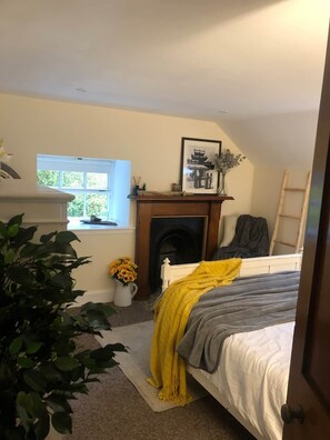 A bedroom with a bed, a fireplace, a window, and a plant. - Pet-Friendly Woodland Escape, 30 acres, Turriff. (Turriff)