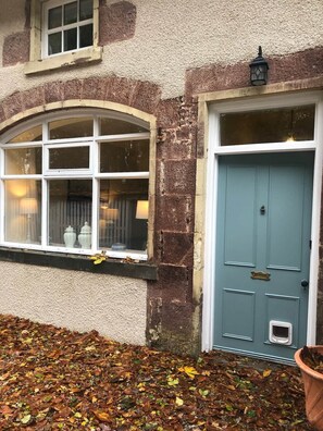 A building with a stone facade, a window with curtains, and a blue door with a knocker. - Pet-Friendly Woodland Escape, 30 acres, Turriff. (Turriff)