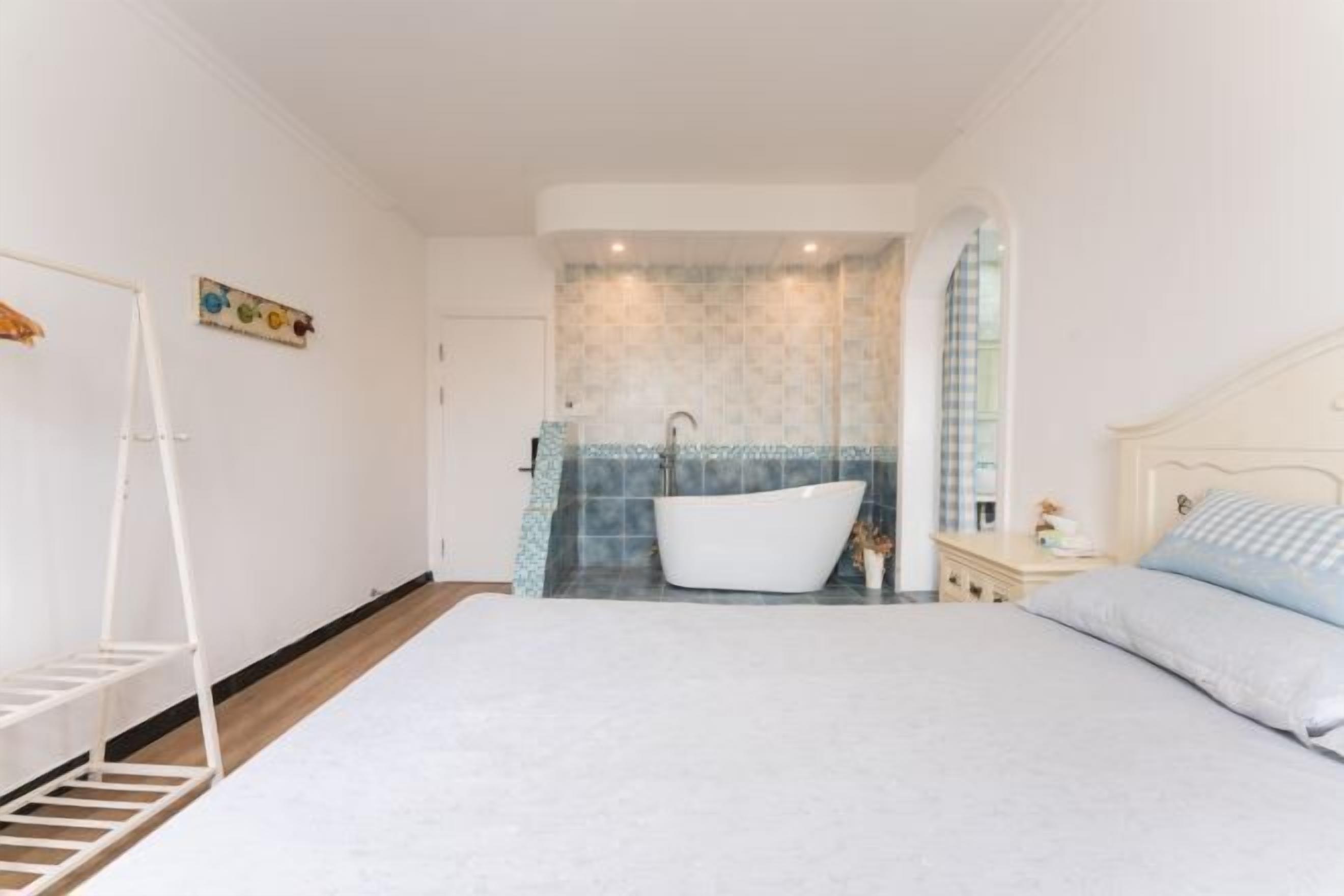 Une chambre à coucher avec un grand lit, une baignoire blanche et une petite table de chevet.