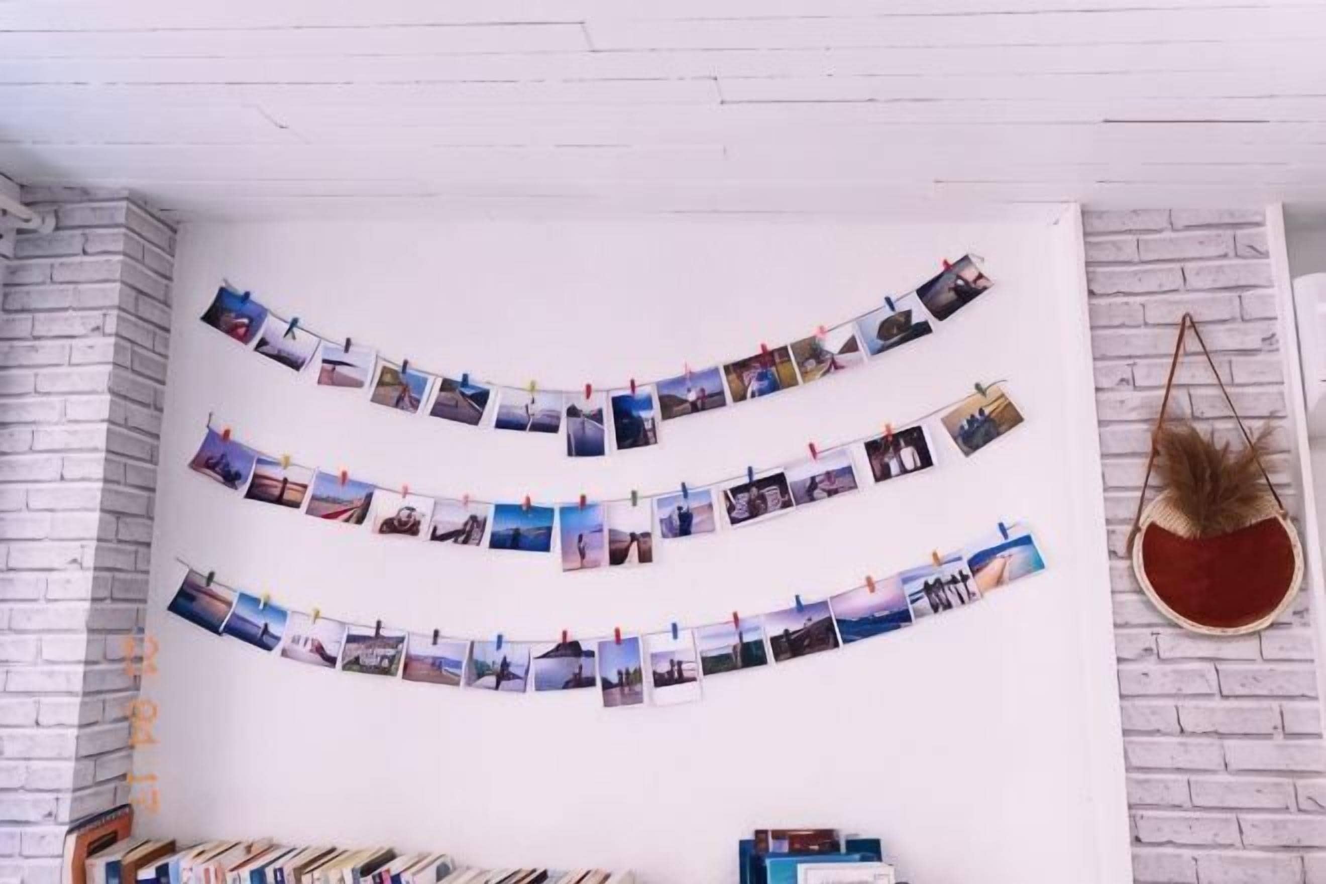 Una habitación con pared de ladrillo blanco, una guirnalda de fotografías y un sillón colgante.