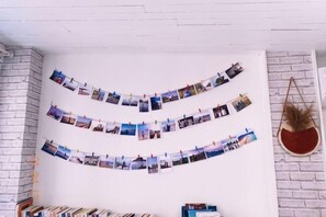 Um quarto com parede de tijolos brancos, uma fileira de fotografias e uma cadeira suspensa.