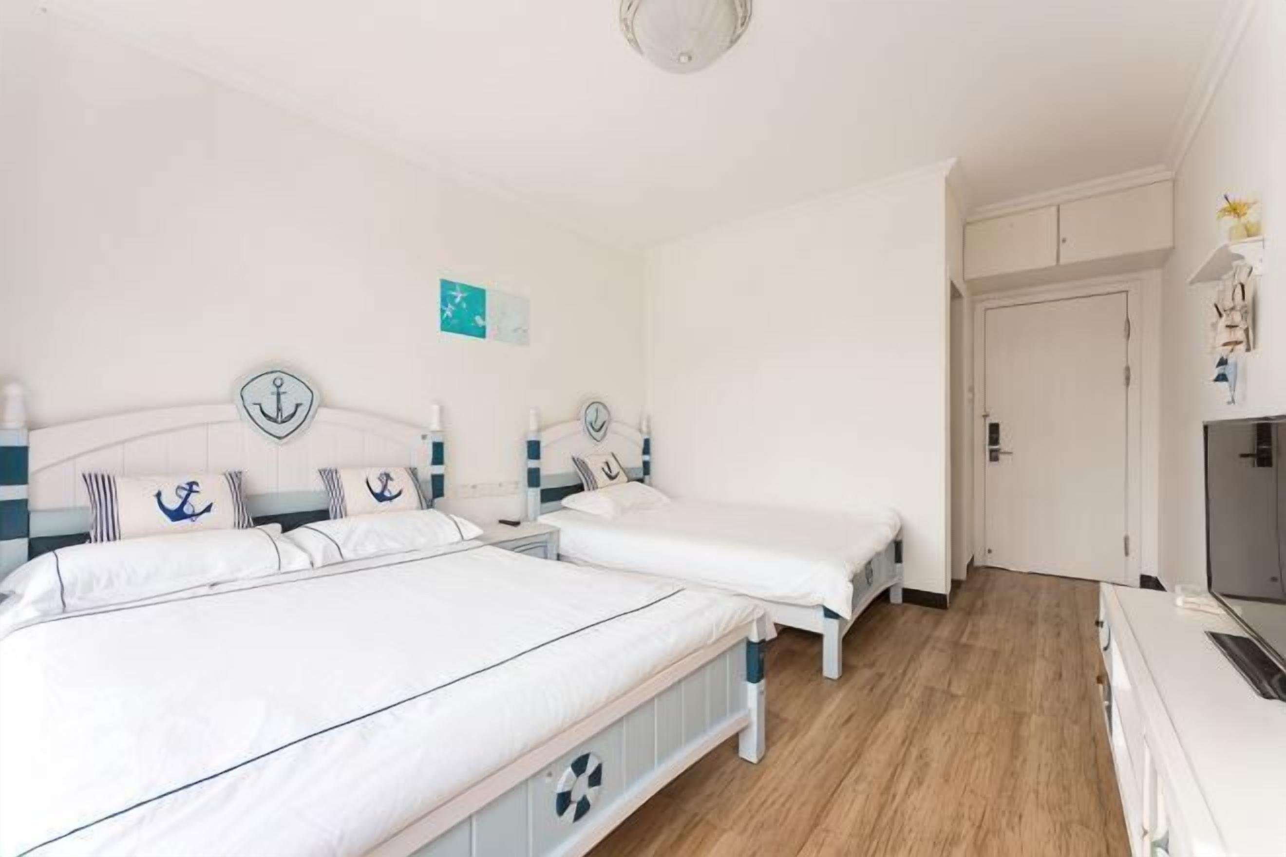 A bedroom with two beds, a TV, and a door.