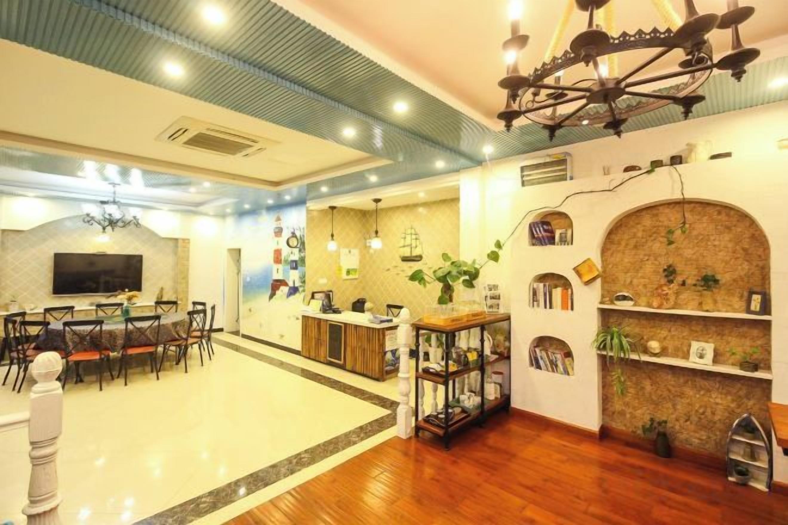 A hotel lobby with a dining area, a reception desk, and a bookshelf.