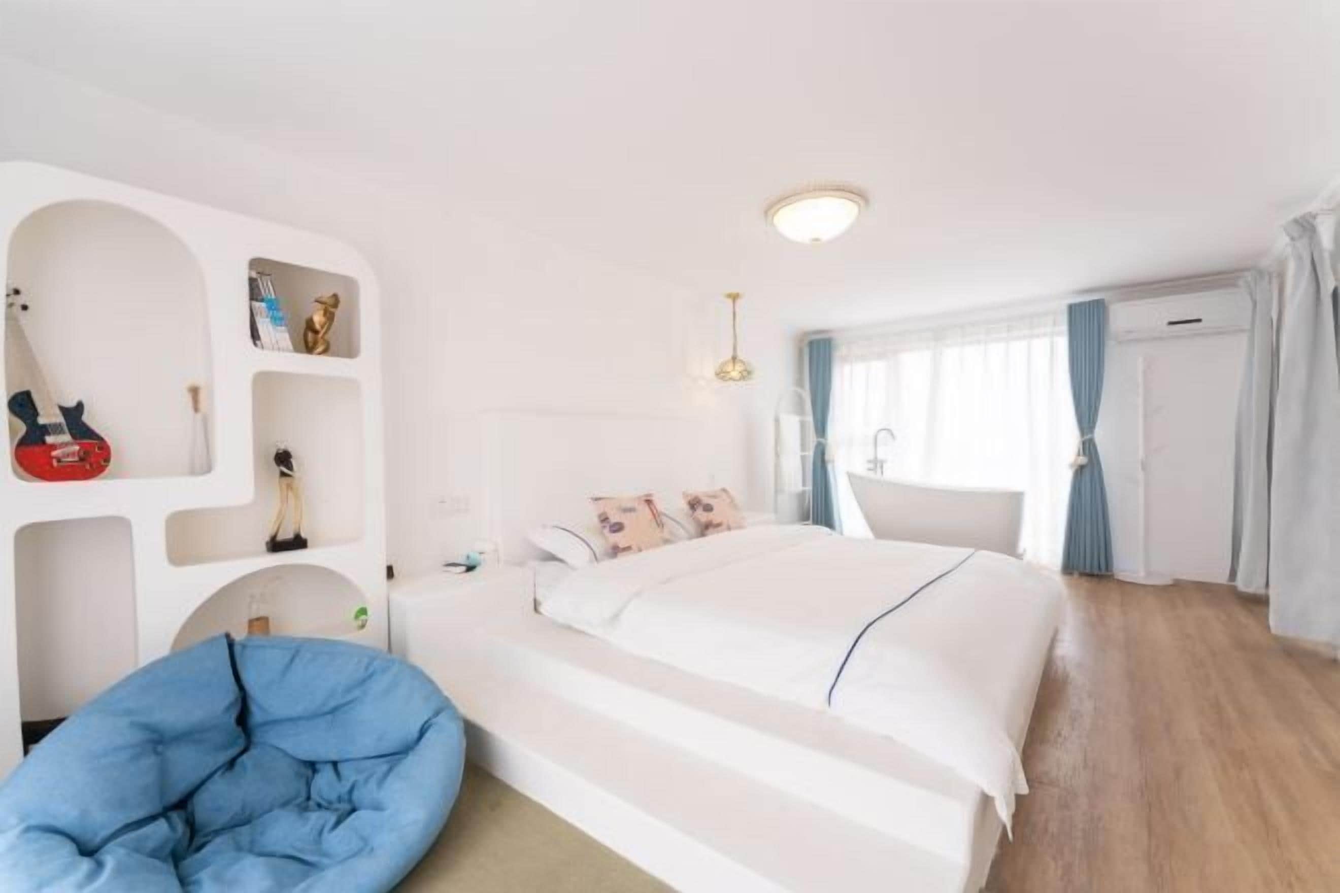 Hotelkamer met een bed, bureau, stoel, kast en een inbouwkast met diverse spullen.