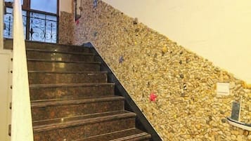 A staircase with a stone wall on one side and a metal railing on the other.