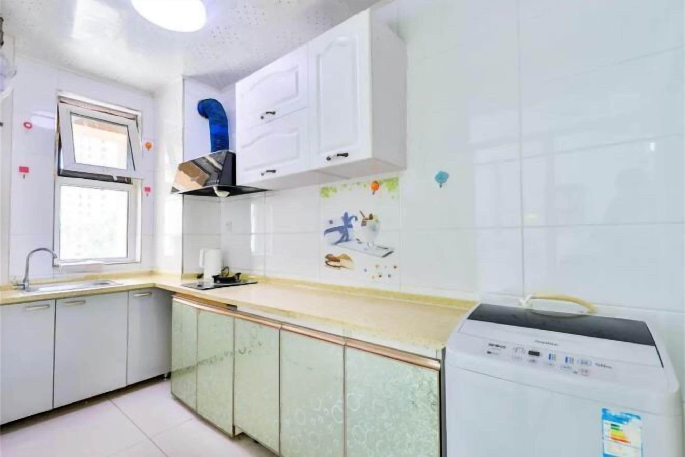 Una cocina con armarios blancos, lavavajillas y ventana.