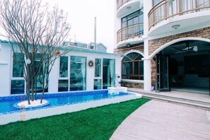 Ein modernes Gebäude mit Schwimmbad, überdachter Terrasse und gepflegtem Rasen.