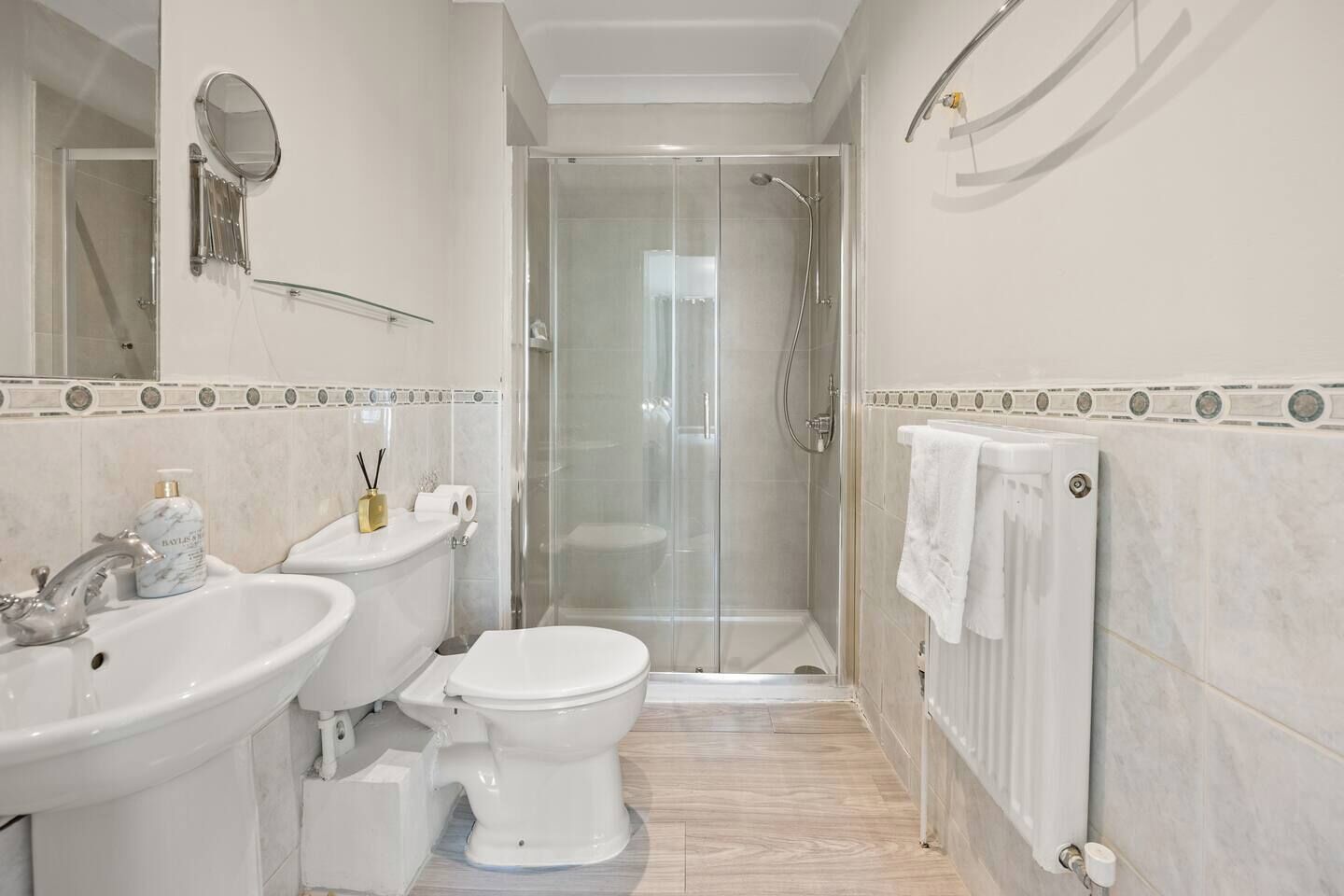 A modern bathroom with a glass-enclosed shower, a double sink, and a toilet.