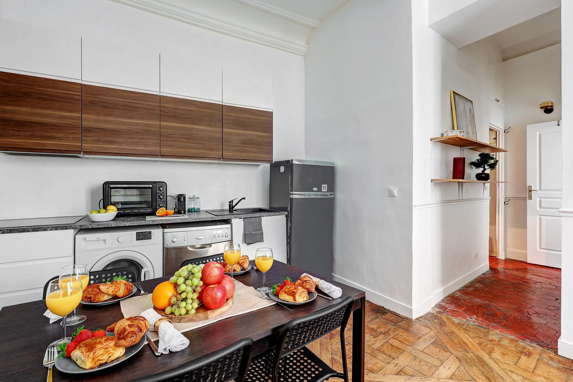 A modern kitchen with a dining area, equipped with a microwave, toaster, and refrigerator.