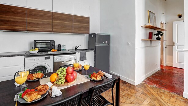 A modern kitchen with a dining area, equipped with a microwave, toaster, and refrigerator. - Stylish 1BR in the Heart of Le Marais (Paris)