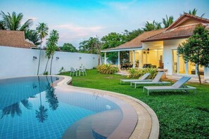 A swimming pool with a tiled deck, surrounded by a grassy area with lounge chairs and a covered patio. - Villa Lia Samui (Koh Samui)