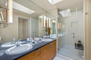 A modern bathroom with three sinks, a glass shower enclosure, and a large mirror. - Stunning Waterfront! Tom Kundig-Designed, Dock, Fire Pit & Bay Views (Seattle)