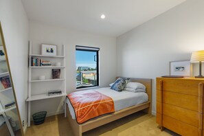 Ein Schlafzimmer mit einem Bett, einem Fenster mit Blick auf die Stadt, einem Bücherregal und einer hölzernen Kommode.