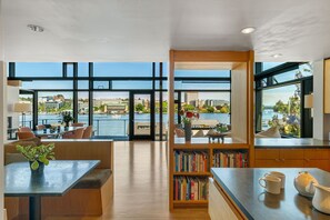 Eine moderne Küche mit Blick auf das Wasser, mit Holzschränken und einem Bücherregal mit Büchern.
