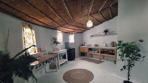 A compact kitchen with a wooden ceiling, a dining table, and a bar area. - Lemon & Co (Bela-Bela)