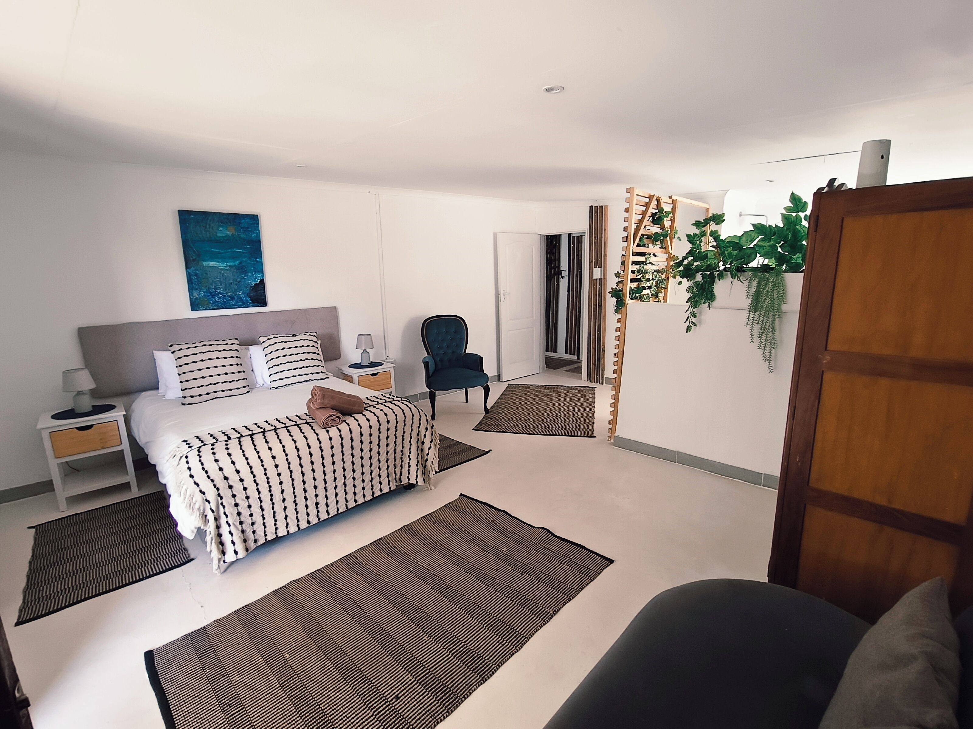 Une chambre moderne avec un lit, des tables de chevet, une chaise et une grande fenêtre.