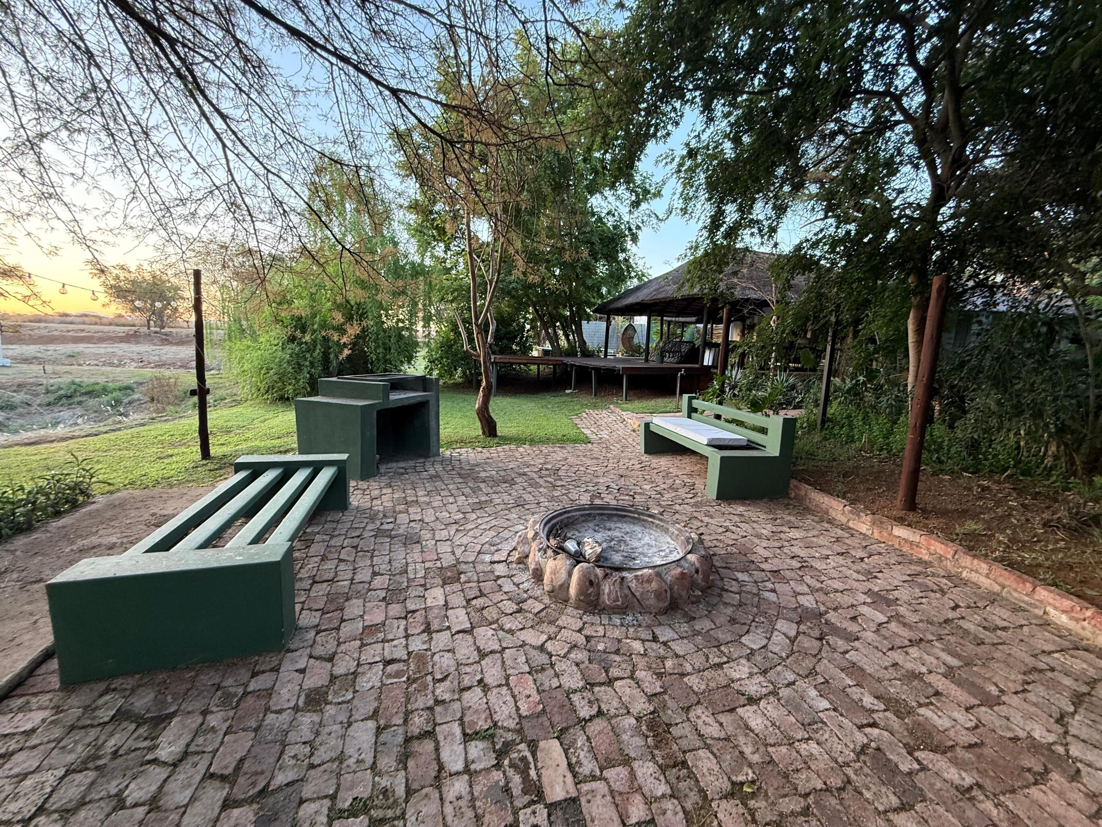 Un espace extérieur aménagé avec un foyer, des bancs et un belvédère.