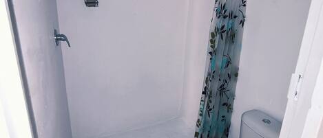 Un baño pequeño y funcional con ducha, inodoro y lavamanos.