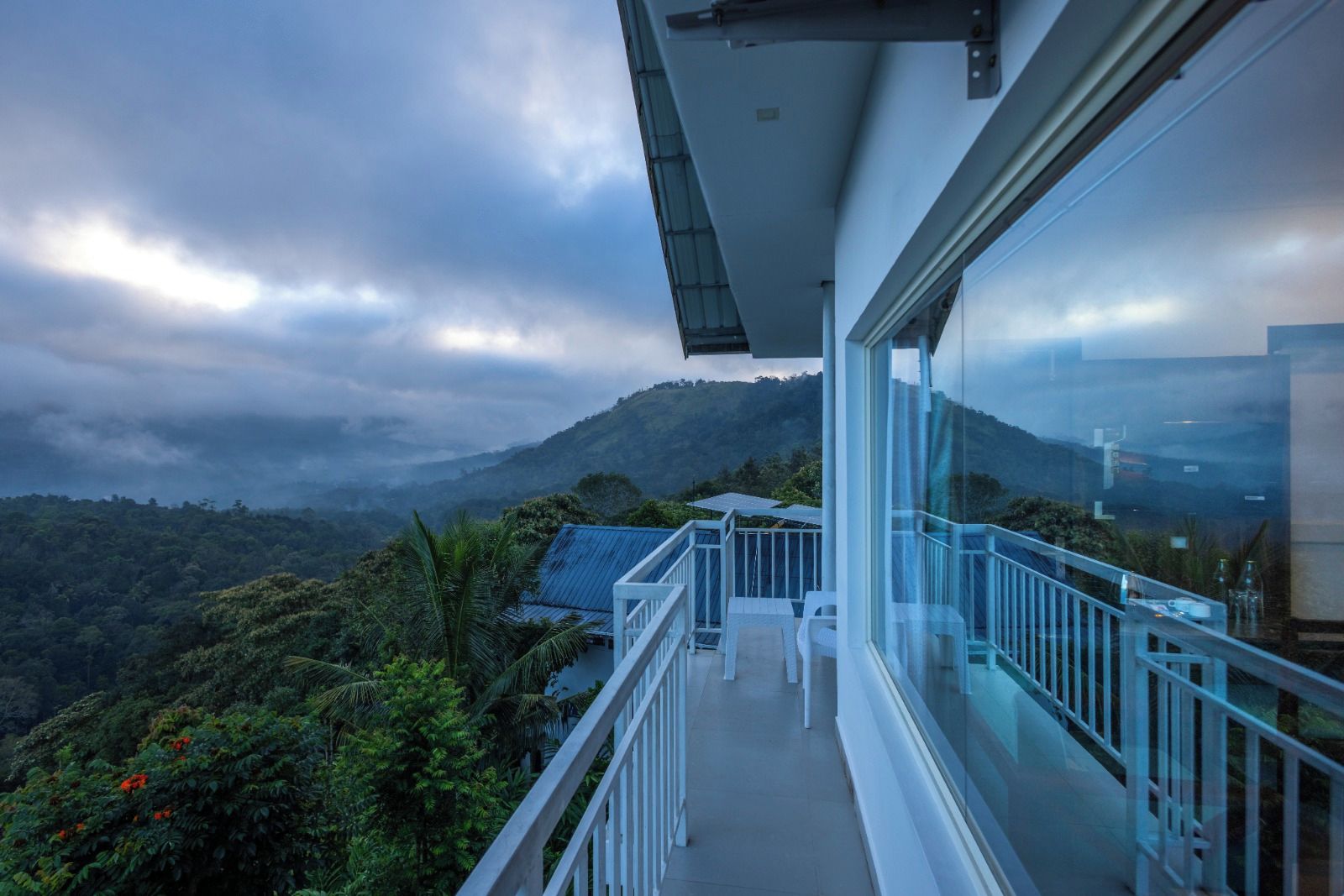 Un balcon doté d’une balustrade en verre, offrant une vue sur un paysage montagneux.