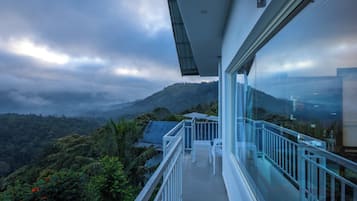 Un balcón con barandilla de cristal con vistas a un paisaje montañoso.