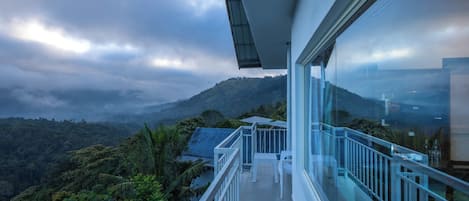 A balcony with a glass railing overlooking a mountainous landscape.